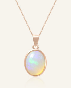 Close-up of the Lumos Opal Necklace in rose gold, resting on a warm linen background