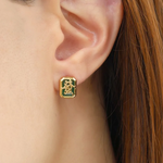 A model wearing a pair of mahjong-themed stud earrings set in yellow gold, featuring one stud with a red agate stone displaying the Hong Zhong (Red Dragon) tile, and the other with a green agate stone adorned with the Qing Fa (Green Dragon) symbol.