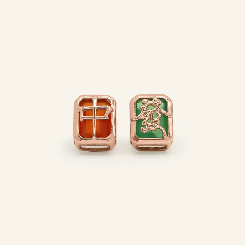 A pair of mahjong-themed stud earrings set in rose gold, featuring one stud with a red agate stone displaying the Hong Zhong (Red Dragon) tile, and the other with a green agate stone adorned with the Qing Fa (Green Dragon) symbol.