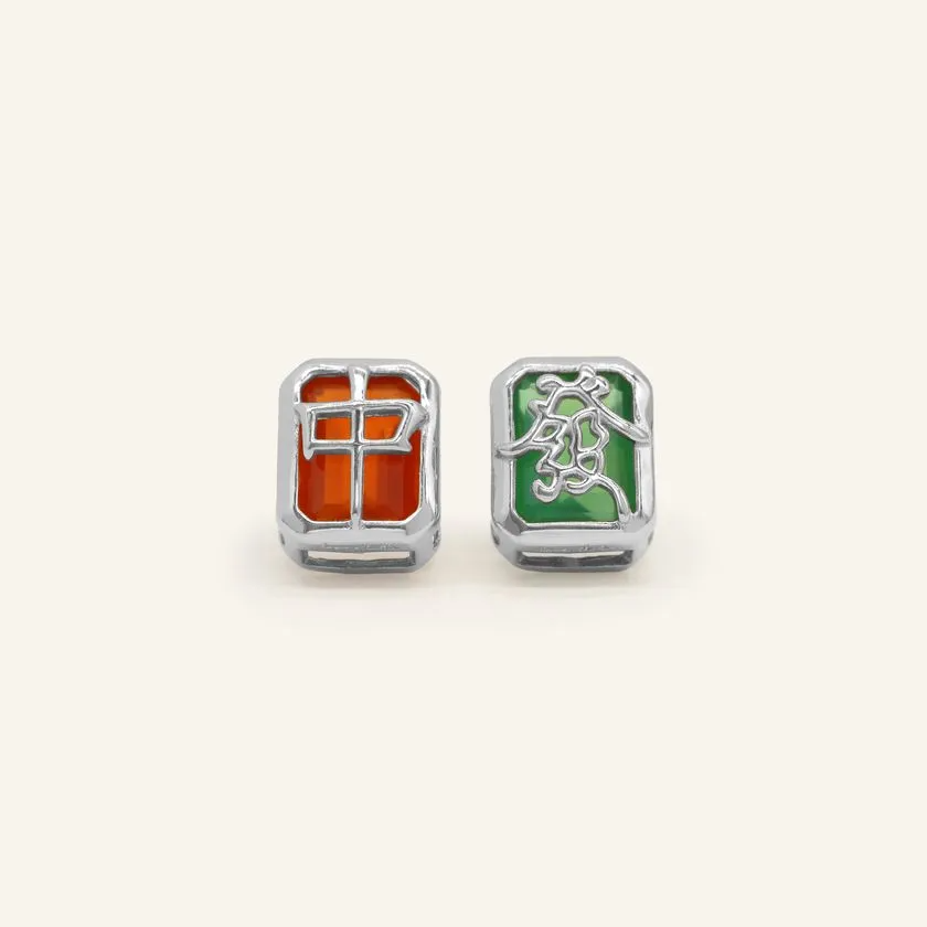 A pair of mahjong-themed stud earrings set in silver, featuring one stud with a red agate stone displaying the Hong Zhong (Red Dragon) tile, and the other with a green agate stone adorned with the Qing Fa (Green Dragon) symbol.