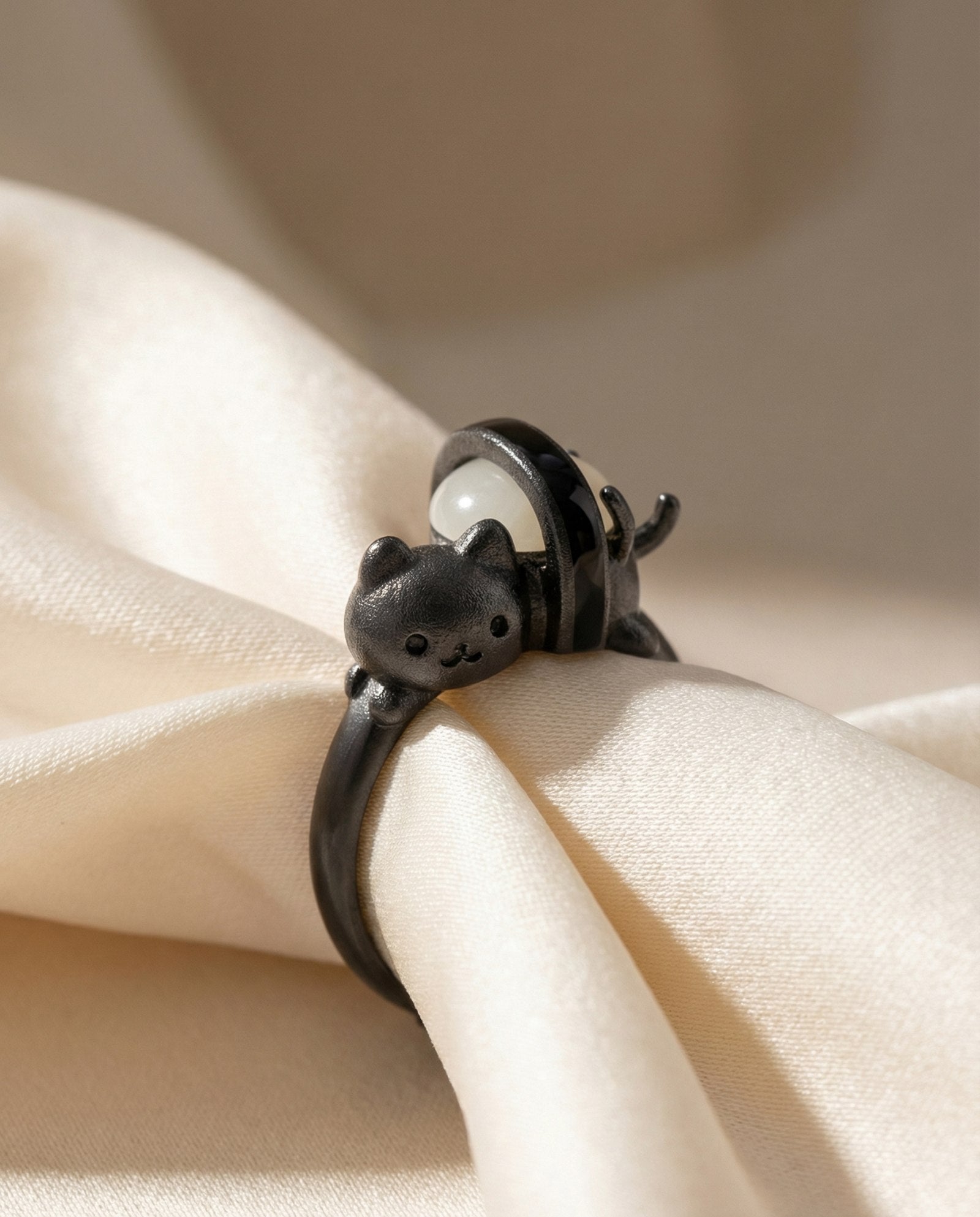 Maki Meow Sushi Ring | White Jade in black gold, laid flat on a tabletop