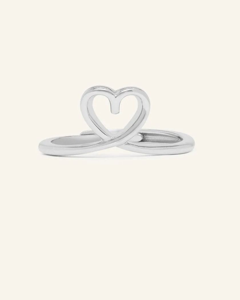 A delicate silver midi heart ring featuring a small, open heart design formed by the intertwining of the band, sitting elegantly on the finger.