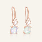 Close-up of the Atlas Opal Ear Drops in rose gold, resting on a warm linen background