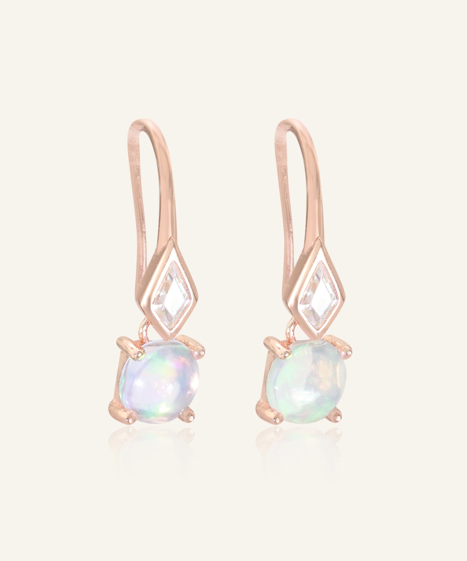 Close-up of the Atlas Opal Ear Drops in rose gold, resting on a warm linen background