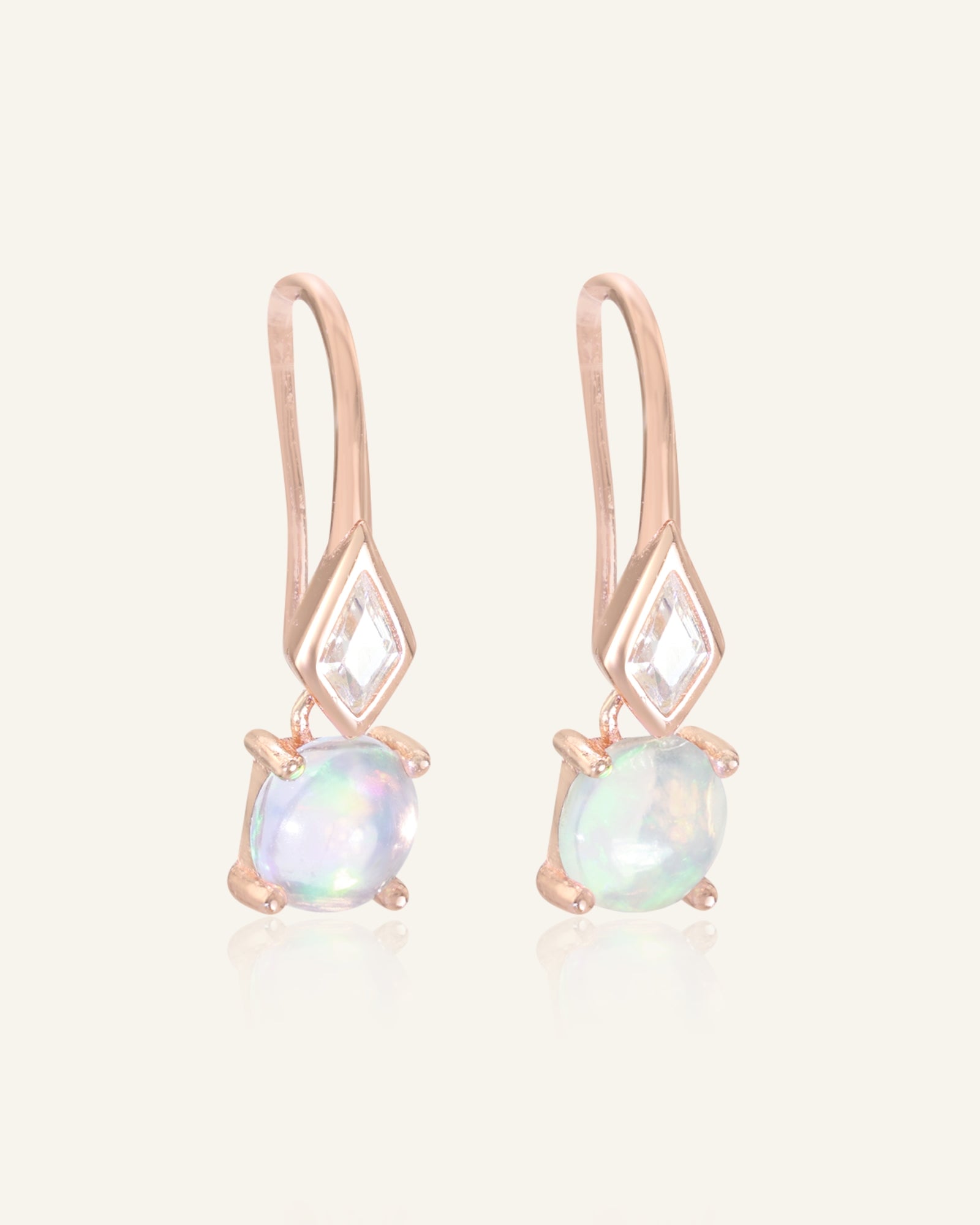 Close-up of the Atlas Opal Ear Drops in rose gold, resting on a warm linen background