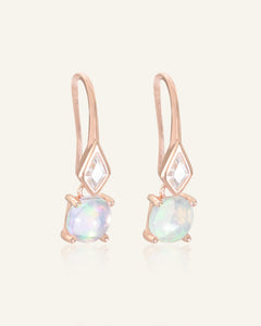 Close-up of the Atlas Opal Ear Drops in rose gold, resting on a warm linen background