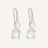Atlas Opal Ear Drops in silver, resting on a warm linen background
