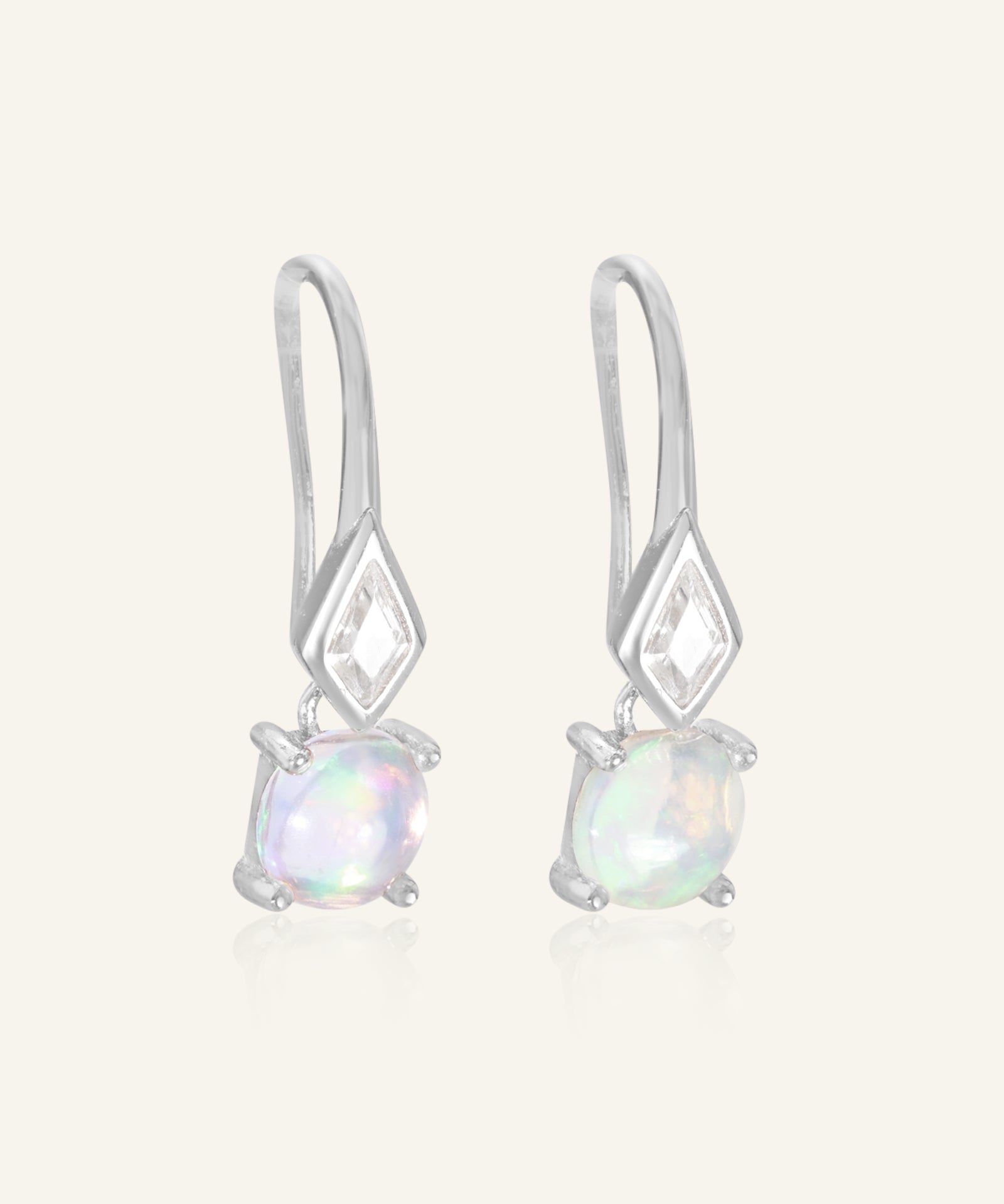 Atlas Opal Ear Drops in silver, resting on a warm linen background