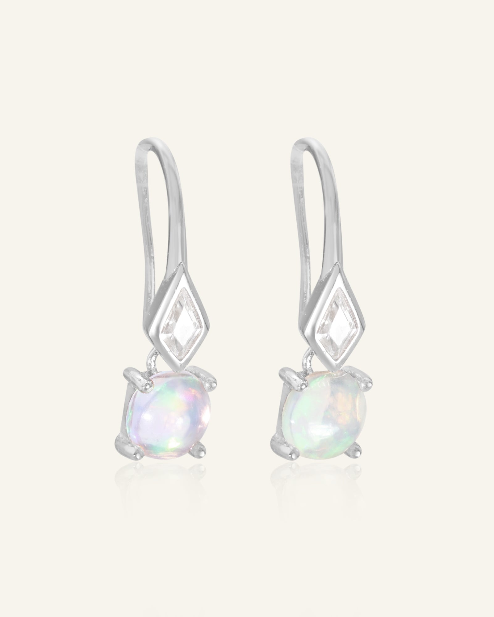 Atlas Opal Ear Drops in silver, resting on a warm linen background