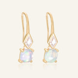 Atlas Opal Ear Drops in yellow gold, resting on a warm linen background