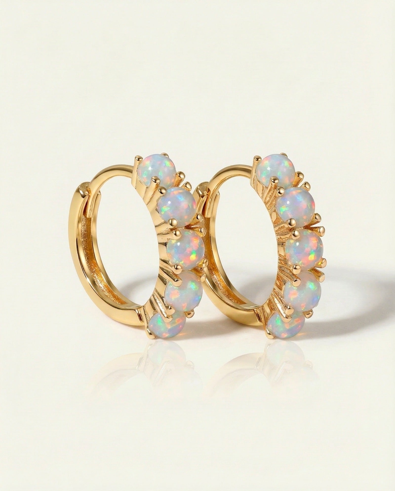 Lumi Opal Hoops in yellow gold, resting on a warm linen background