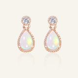 Close-up of the Suri Opal Teardrop Studs in rose gold, resting on a warm linen background