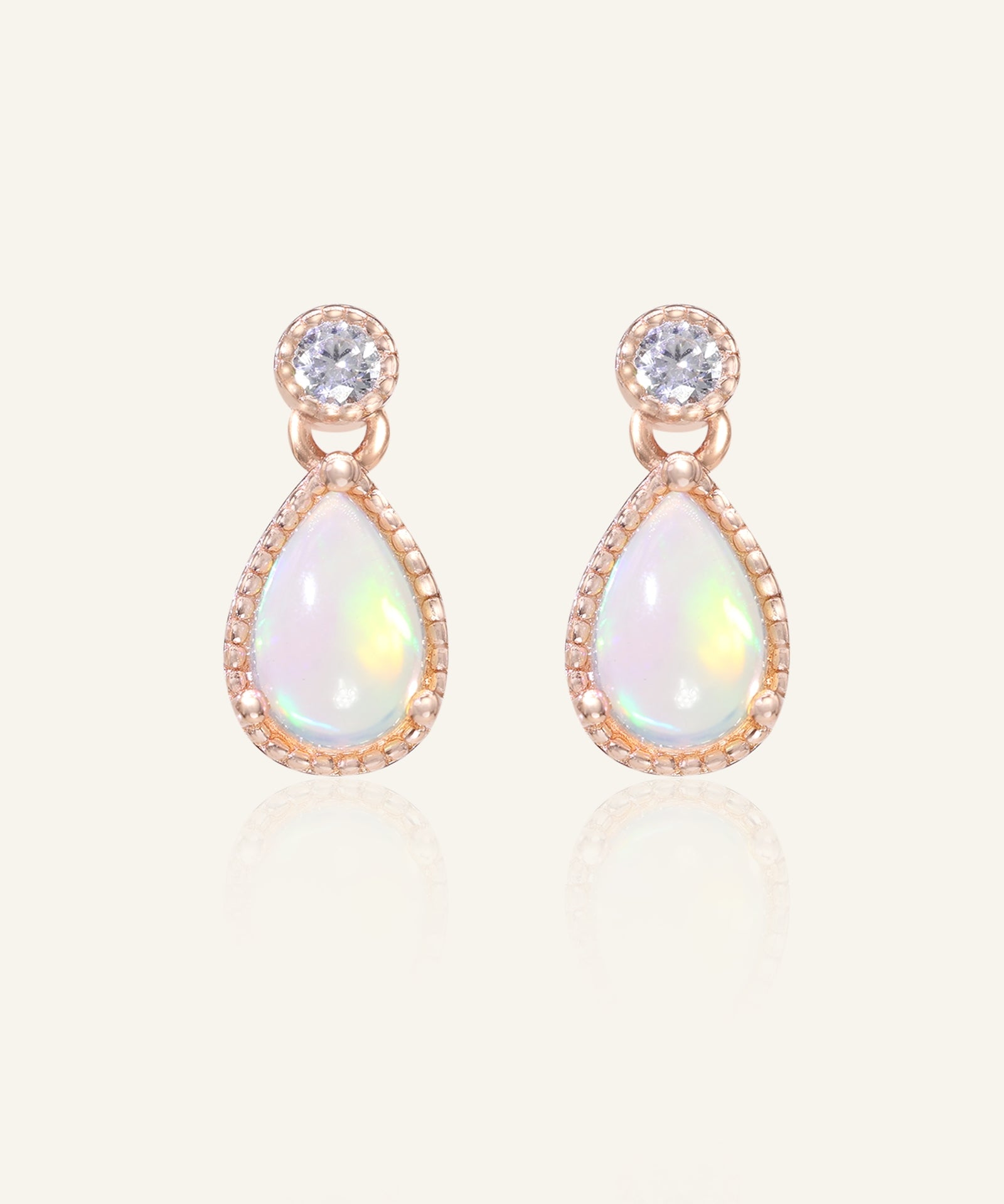 Close-up of the Suri Opal Teardrop Studs in rose gold, resting on a warm linen background