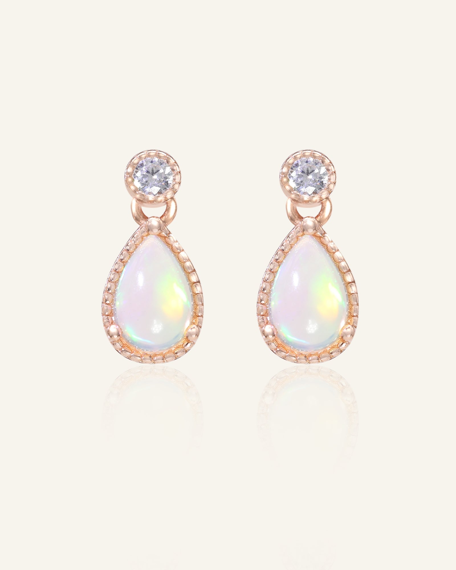 Close-up of the Suri Opal Teardrop Studs in rose gold, resting on a warm linen background