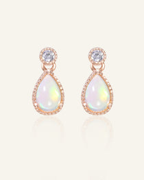Close-up of the Suri Opal Teardrop Studs in rose gold, resting on a warm linen background