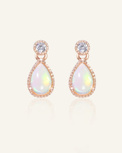 Close-up of the Suri Opal Teardrop Studs in rose gold, resting on a warm linen background