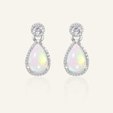 Suri Opal Teardrop Studs in silver, resting on a warm linen background