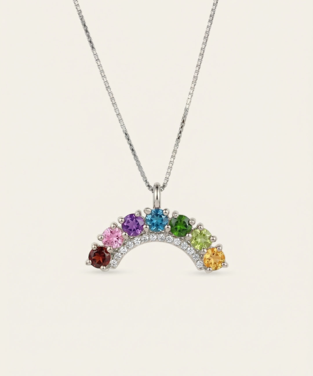 Symmetrical front view of a silver rainbow gemstone crescent arch pendant necklace on a clean minimal backdrop.