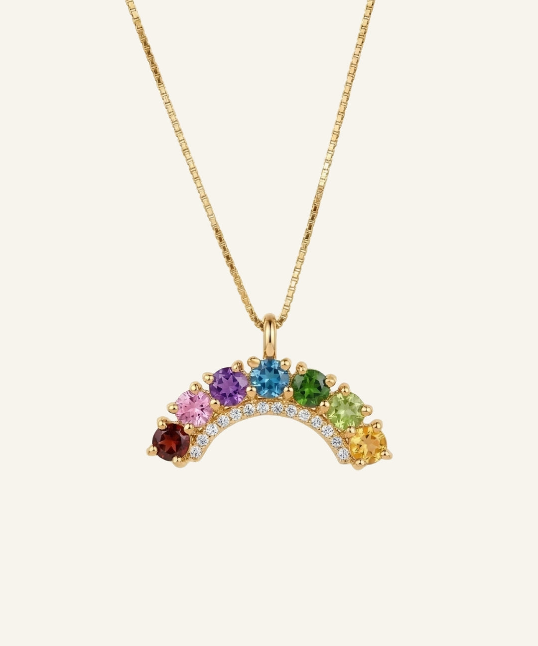 Studio flat-lay of an 18k yellow gold rainbow arc necklace featuring a flawless natural gemstone color gradient.