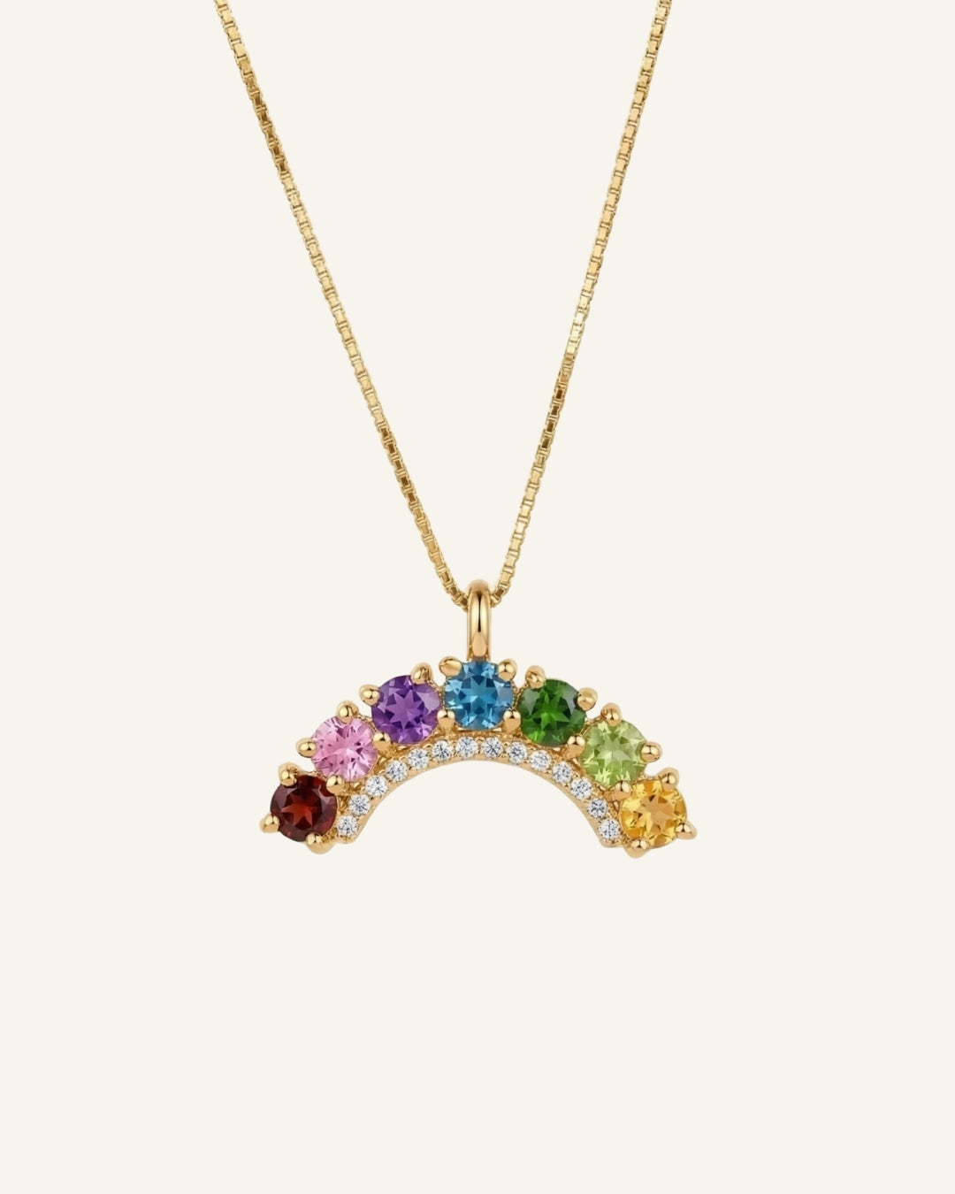 Studio flat-lay of an 18k yellow gold rainbow arc necklace featuring a flawless natural gemstone color gradient.