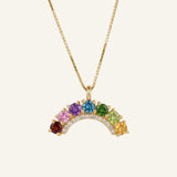 Studio flat-lay of an 18k yellow gold rainbow arc necklace featuring a flawless natural gemstone color gradient.