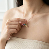Model styling a dainty 18k rose gold vermeil rainbow arch gemstone necklace along the collarbone.
