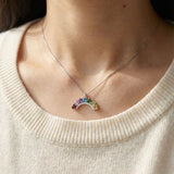 Model wearing a 925 sterling silver rainbow arc necklace with natural gradient gemstones against a cream knit sweater.