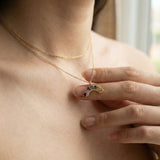 Close-up of a model wearing a yellow gold multi-gemstone rainbow crescent pendant necklace, showcasing the scale.