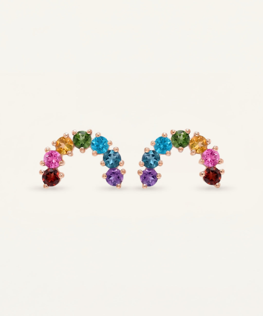 Pair of rose gold multi-gemstone rainbow arc stud earrings displaying a symmetrical vibrant crystal gradient.