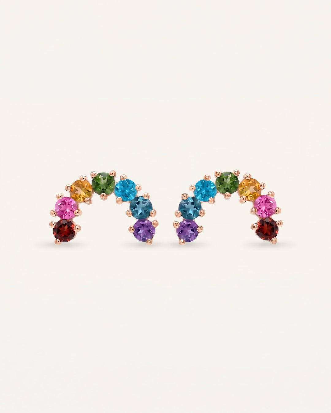 Pair of rose gold multi-gemstone rainbow arc stud earrings displaying a symmetrical vibrant crystal gradient.