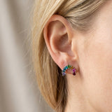 Blonde model wearing a silver rainbow gradient arc ear climber earring with natural gemstones on earlobe.