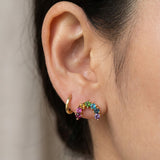 Side profile of a model styling a yellow gold rainbow multi-gemstone arc stud earring next to a small gold hoop.
