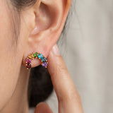 Model pointing to a yellow gold rainbow arc climber earring featuring a colorful natural gemstone gradient.