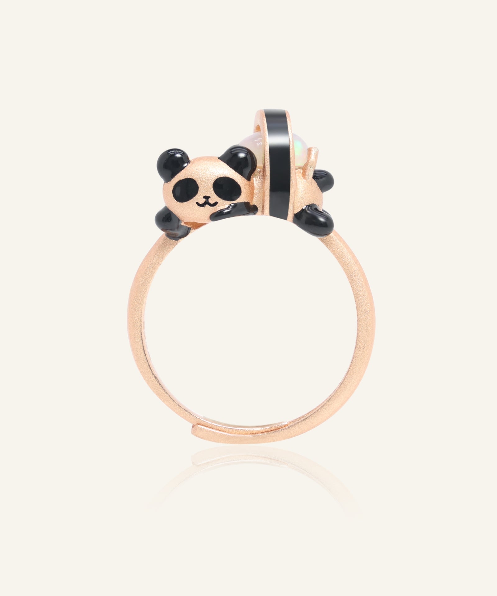 Close-up of the Panda Sushi Roll Ring (Opal) in rose gold, resting on a warm linen background