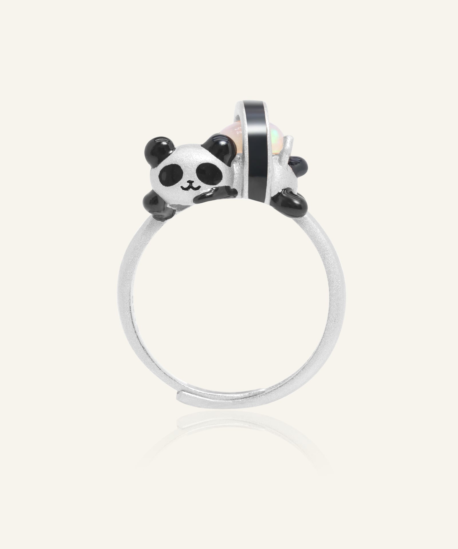 Panda Sushi Roll Ring (Opal) in silver, resting on a warm linen background