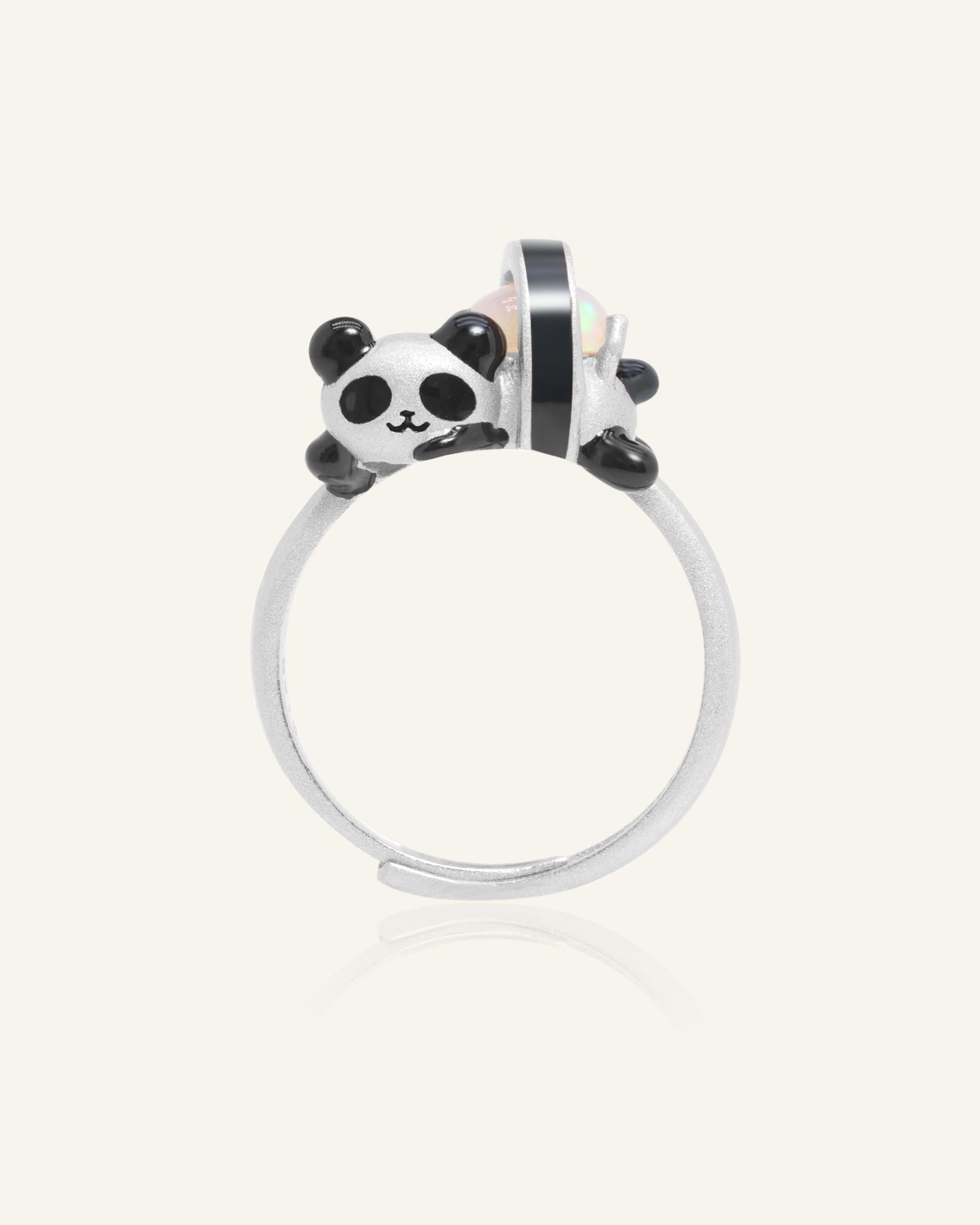 Panda Sushi Roll Ring (Opal) in silver, resting on a warm linen background