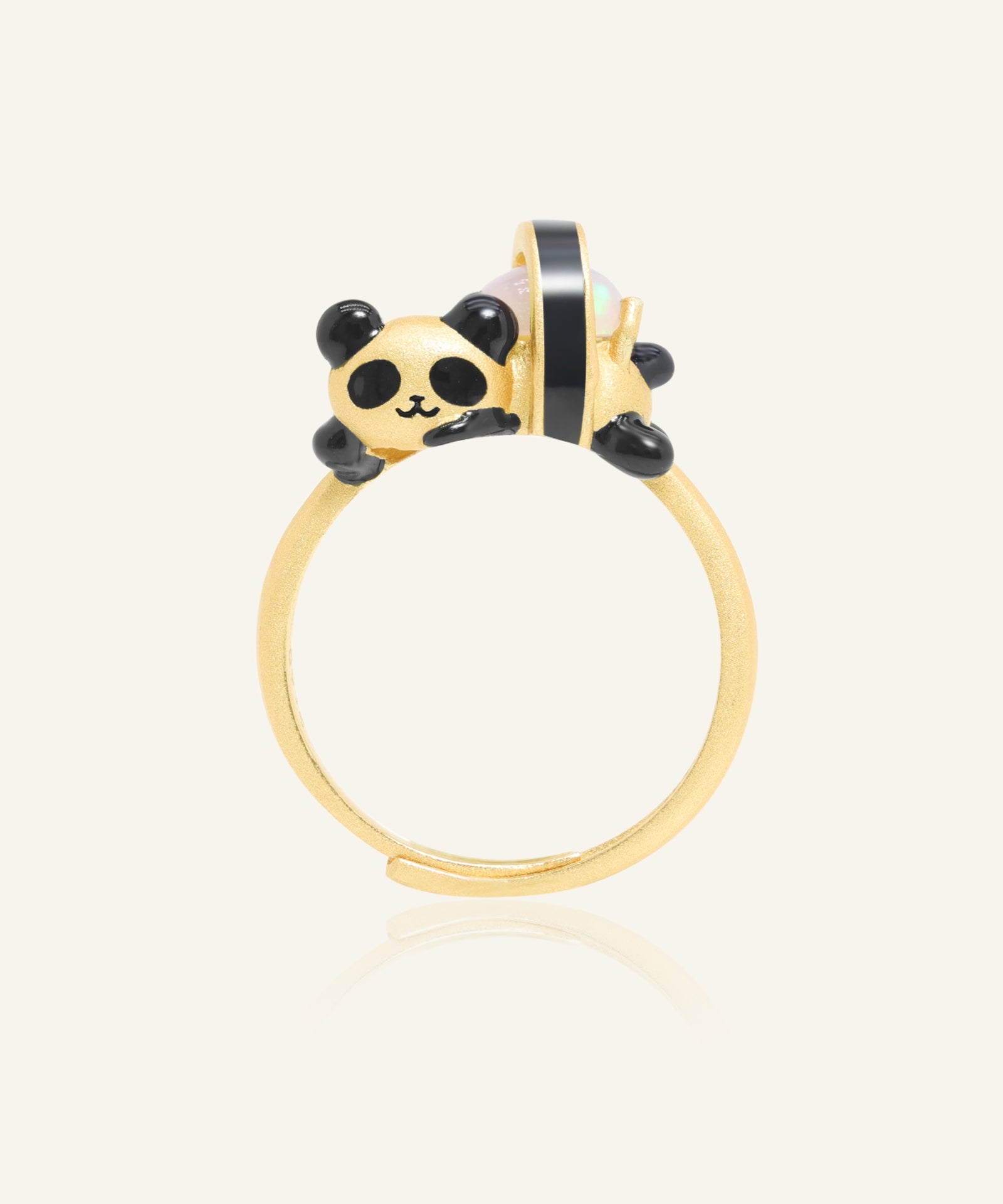 Panda Sushi Roll Ring (Opal) in yellow gold, resting on a warm linen background
