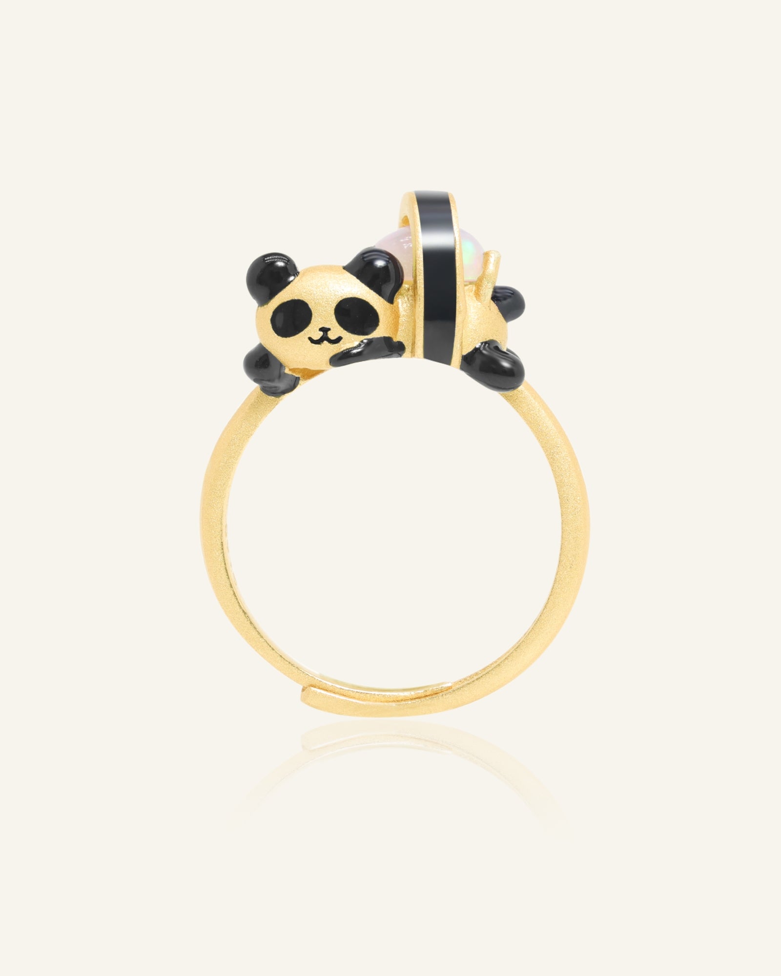 Panda Sushi Roll Ring (Opal) in yellow gold, resting on a warm linen background