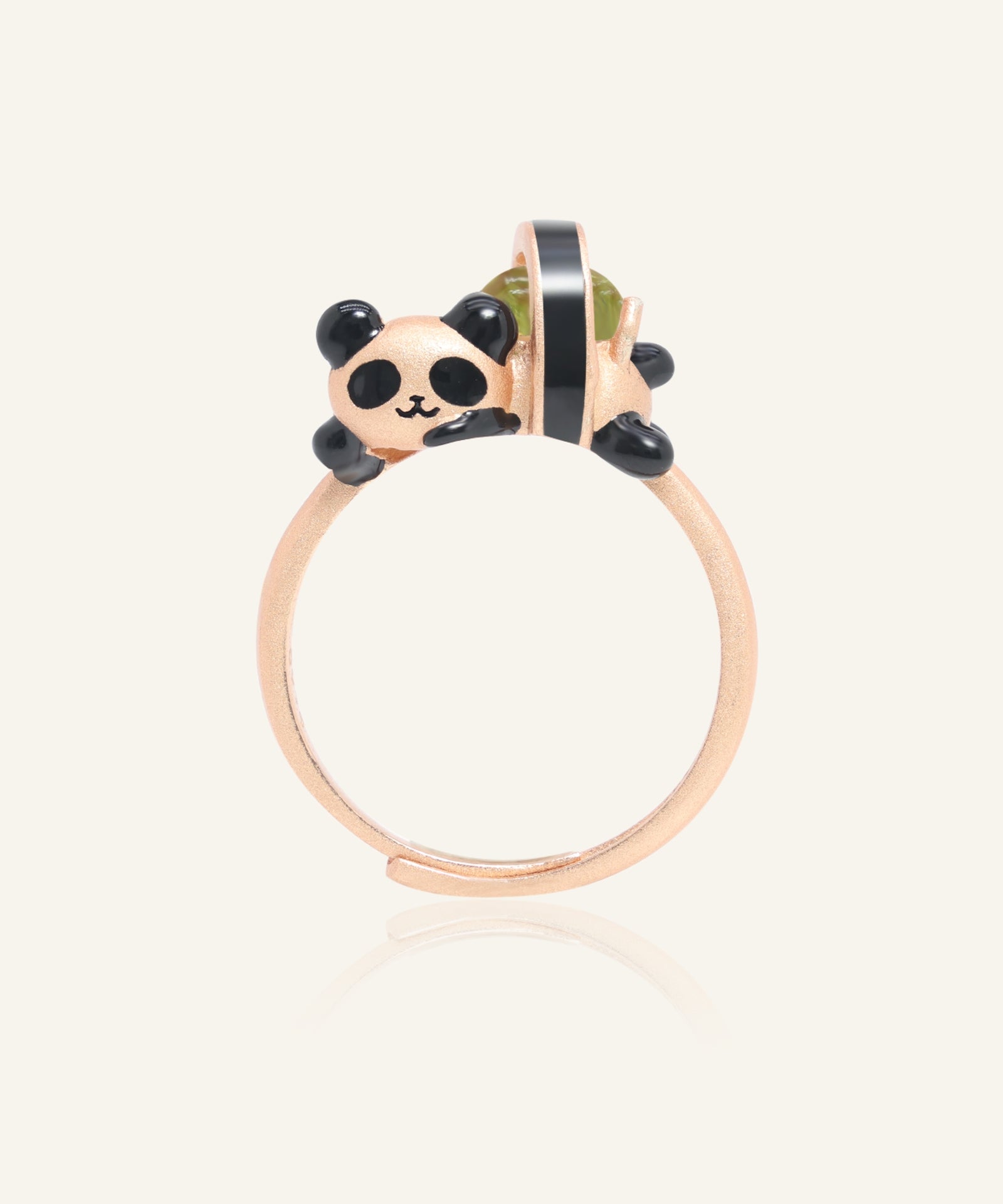 Panda Sushi Roll Ring (Peridot) in rose gold, resting on a warm linen background