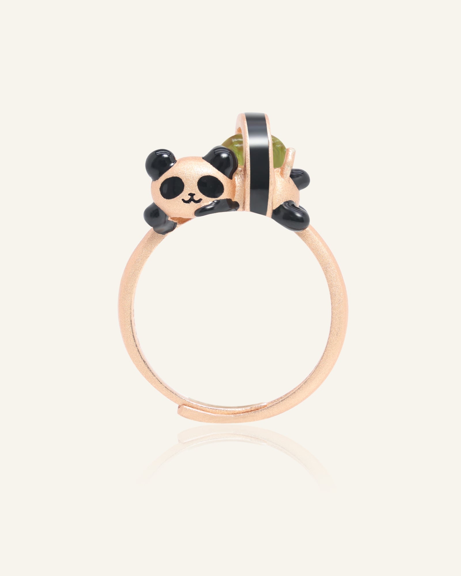 Panda Sushi Roll Ring (Peridot) in rose gold, resting on a warm linen background