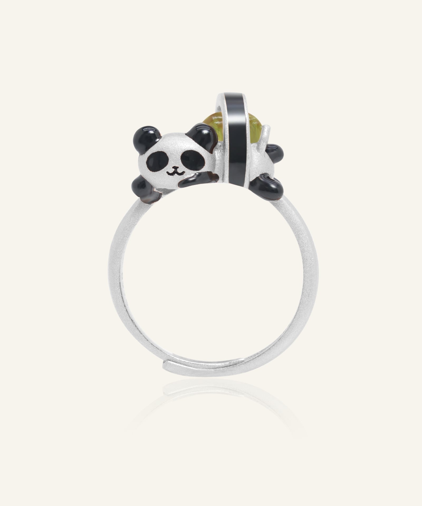 Close-up of the Panda Sushi Roll Ring (Peridot) in silver, resting on a warm linen background