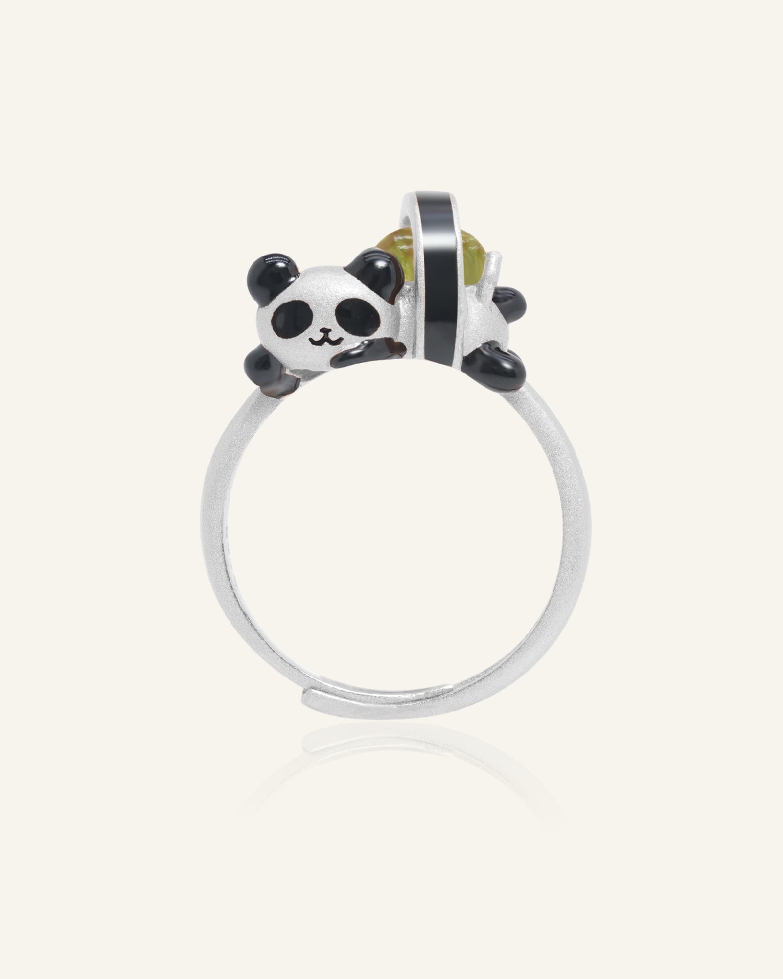 Close-up of the Panda Sushi Roll Ring (Peridot) in silver, resting on a warm linen background