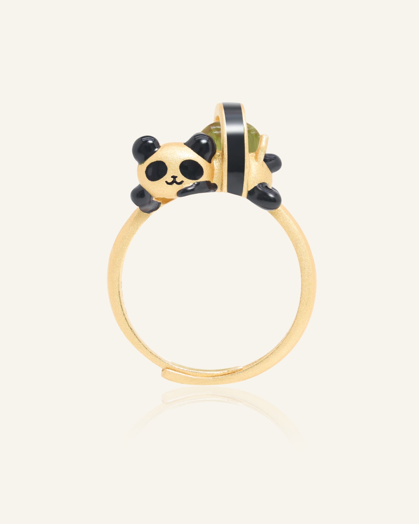 Panda Sushi Roll Ring (Peridot) in yellow gold, resting on a warm linen background