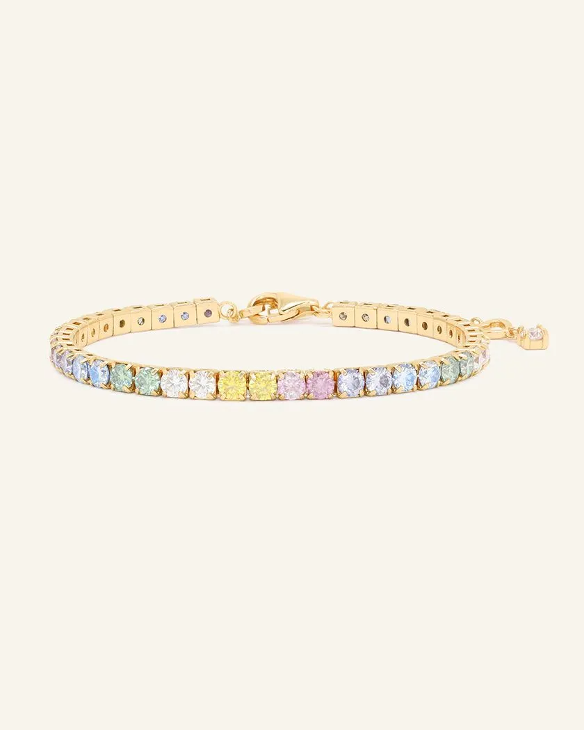 A pastel moissanite tennis bracelet featuring a row of round-cut moissanite stones in soft shades of ice blue, green, yellow, pink, and lilac, set in yellow gold.