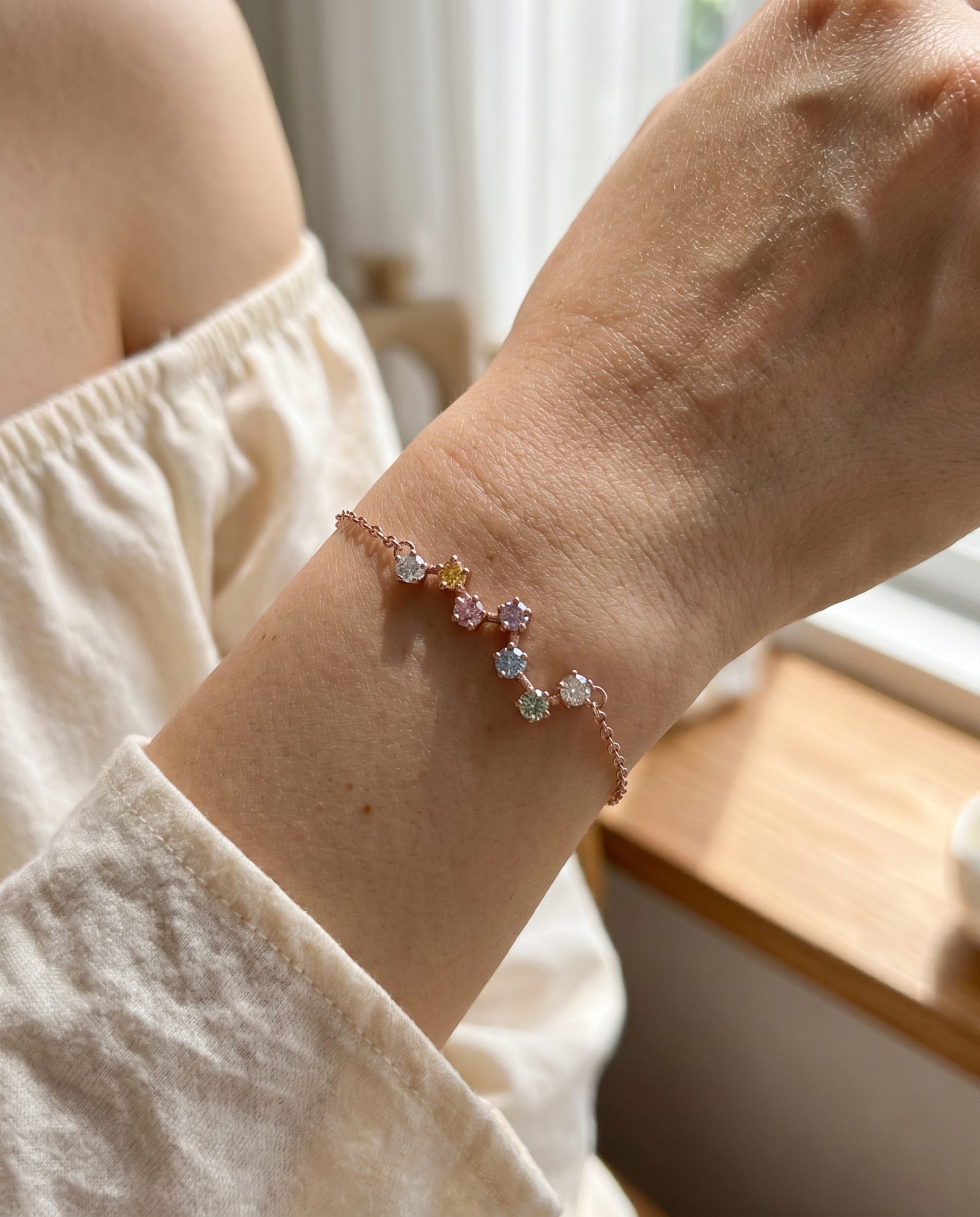 A lifestyle photograph of the rose gold Pastel Constellation Moissanite Bracelet worn elegantly on a model's wrist, highlighting how the delicate star-cluster layout sits beautifully as a standalone piece.