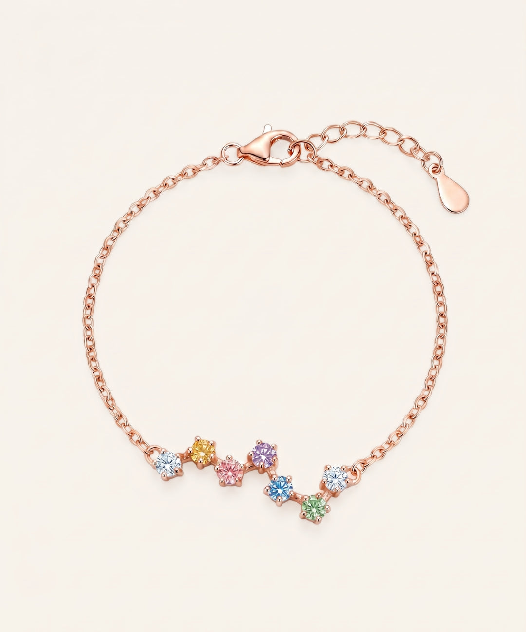 A top-down studio product photograph of the Pastel Constellation Moissanite Bracelet in rose gold, showcasing the delicate cable chain and the curved, zigzag star-cluster setting of multi-colored pastel gemstones.