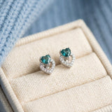 Petite double heart stud earrings featuring teal-blue tourmaline gemstones in a high-quality linen jewelry box.
