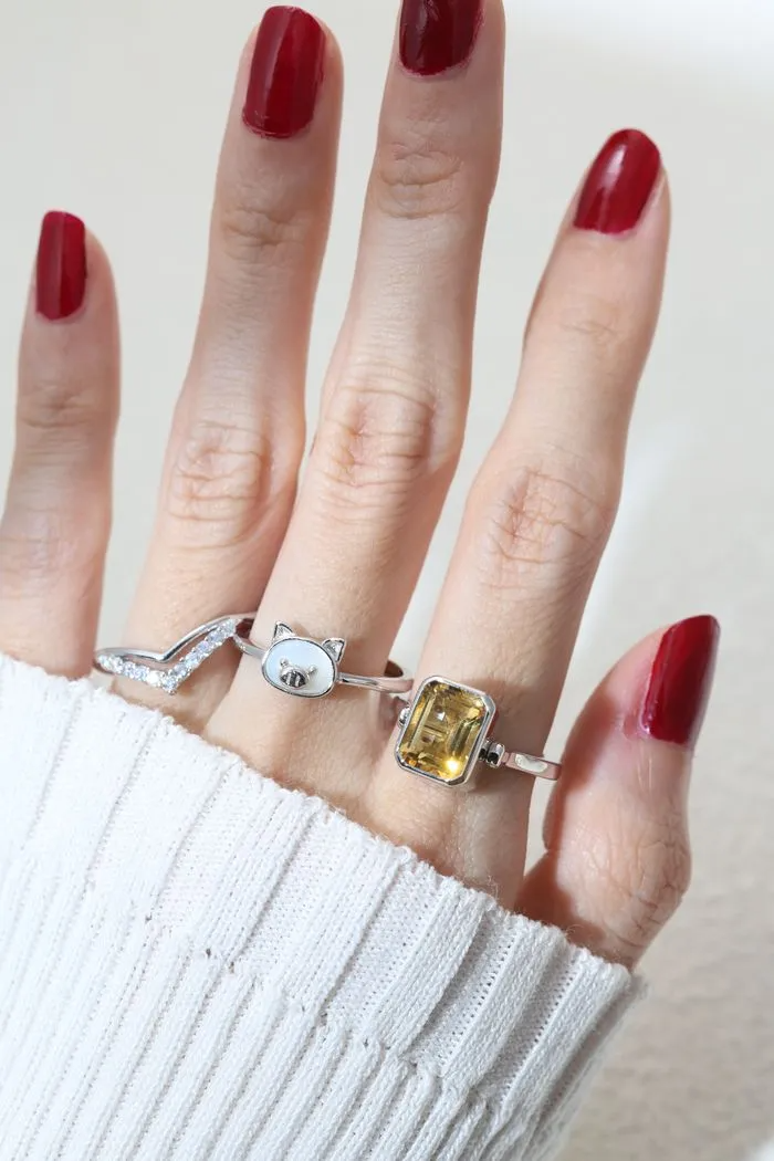 A model wearing a silver ring featuring a mother of pearl centerpiece shaped like a pig's head.