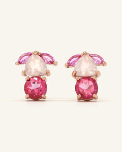 Close-up of the Piglet Origami Studs in rose gold, resting on a warm linen background