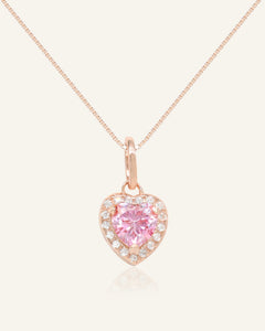 Close-up of the Pink Moissanite Heart Halo Necklace in rose gold, resting on a warm linen background